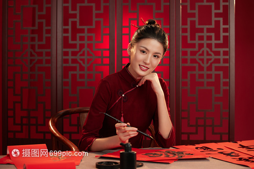 旗袍美女拿着毛笔托着下巴